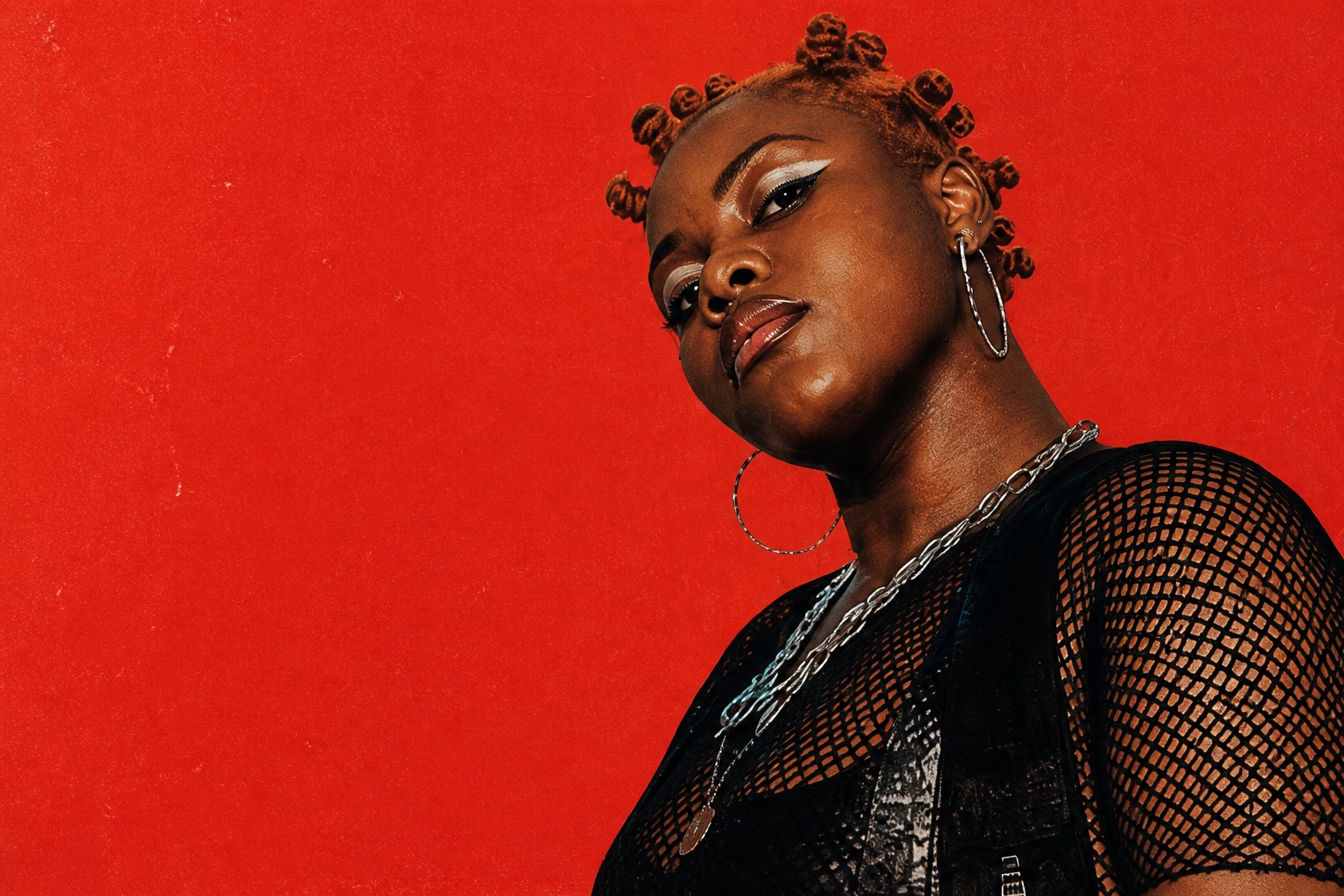 Editorial portrait of an Accra music artist against a vermilion backdrop